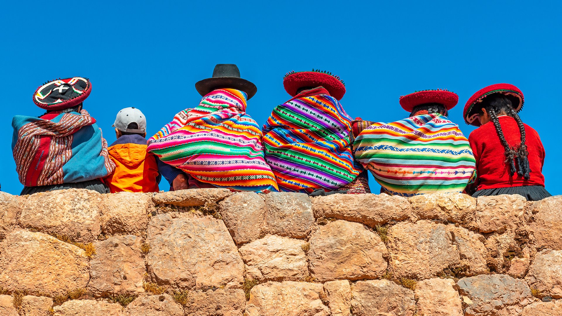 near cusco peru, quechua indigenous women rest on an ancient inca wall